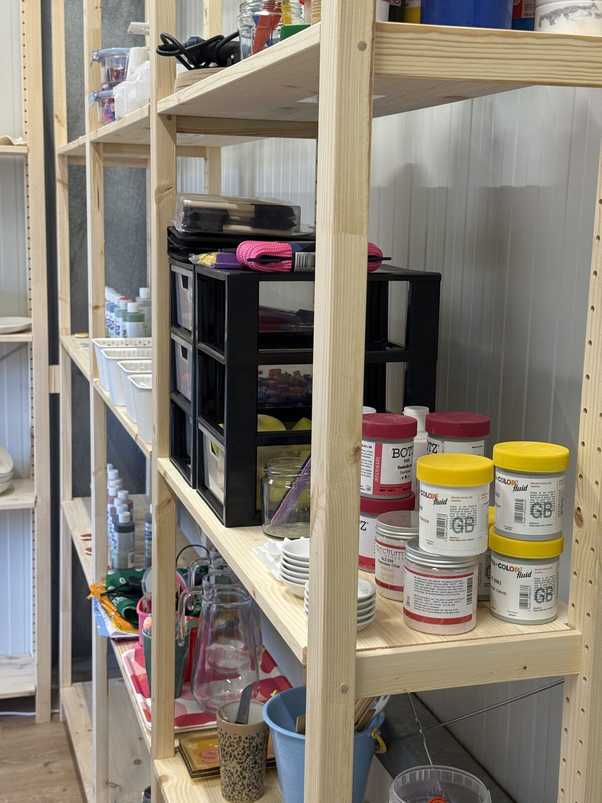 Voorraadkast met verfpotten en knutselmaterialen in het atelier